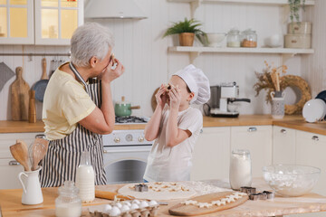 Happy family in kitchen. Grandmother granddaughter child cutting cookies of dough on kitchen table together. Grandma teaching kid girl cook bake cookies. Household teamwork helping family generations
