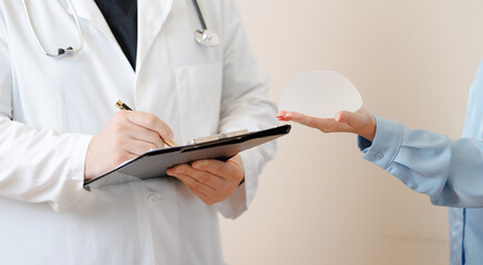 Consultation in plastic clinic with silicone breast implants, doctor and female patient interaction