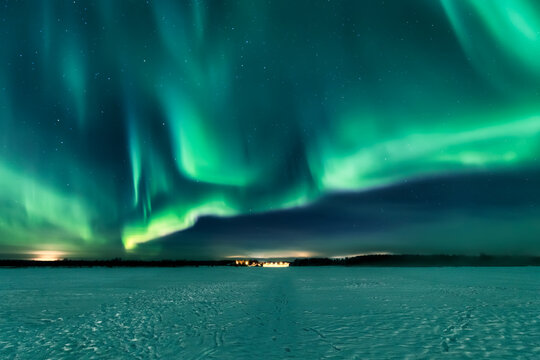 View of the breathtaking Aurora Borealis painting the Arctic sky with vibrant shades of green above the snowy landscape, Rovaniemi, Finland.