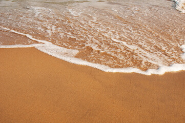 Sandy coastline and sea waves by summer day
