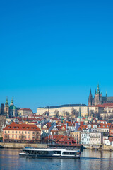 Prague, Czech Republic. Modern electric Boat tour vessel navigating the Vltava River, with historic riverfront buildings