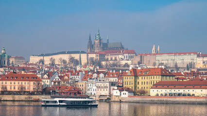 Panoramic view of Prague Castle complex towering over historic Lesser Town and Vltava River. Tour boat. Prague, Czech Republic - February 24, 2025