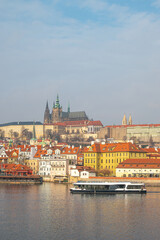 Prague, Czech Republic. Modern electric Boat tour vessel navigating the Vltava River, with historic riverfront building