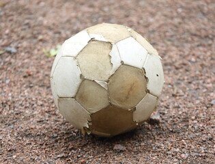 An old, worn-out soccer ball lies on the ground