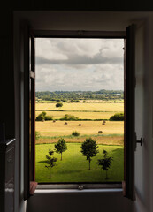 Countryside view of hay bales and tress through a window