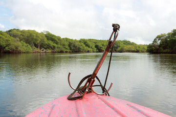 A small anchor tied down on the front of a small boat 