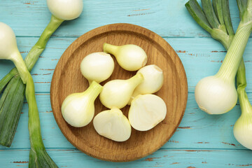 Green onion on wooden plate on blue wooden background.