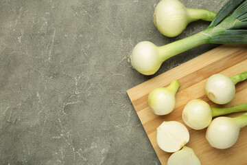 Green onion on cutting board on grey concrete background.