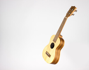 Ukulele on a white background. A guitar made of light wood on a white background. isolated. side...