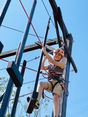 a brave boy in outdoor rope park passing obstacle course. Active summer holidays