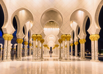 View of ornate white archways and pillars, adorned with golden accents, create a mesmerizing, symmetrical perspective, Abu Dhabi, Abu Dhabi, United Arab Emirates.