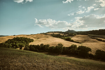 Colline toscane al tramonto con borgo in lontananza.