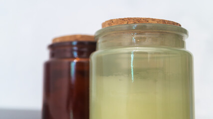 Green and red glass jars with wooden covers on the white table