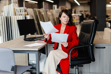 Saleswoman analyzing documents while sitting at desk in furniture store