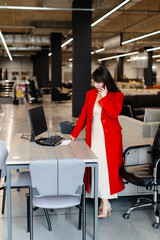 Saleswoman talking on phone and working on computer in furniture store