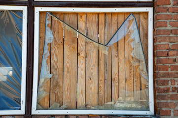 A broken window covered by wooden boards illustrates abandonment in a forgotten building under...