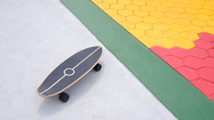 Skateboard on concrete yard floor with colorful hexagon cobblestone pavement decoration in outdoor area
