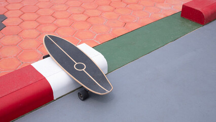 Skateboard on gray concrete yard floor with colorful hexagon cobblestone pavement in outdoor area