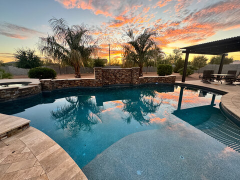 Beautiful desert sunset in an Arizona backyard with a palm tree, pergola / ramada and swimming poo