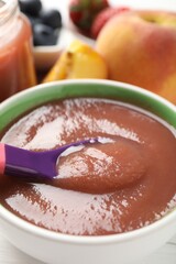 Baby food. Eating tasty puree with spoon at white table, closeup
