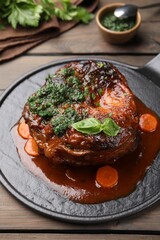 Traditional ossobuco dish with beef steak and sauce served on wooden table, closeup