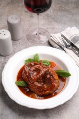 Traditional ossobuco dish with beef steak served on grey table, above view