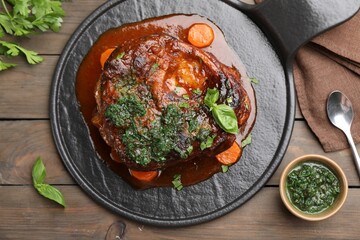 Traditional ossobuco dish with beef steak and sauce served on wooden table, flat lay