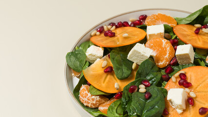 Winter salad. Fresh persimmon and pomegranate spinach salad with feta and pine nuts