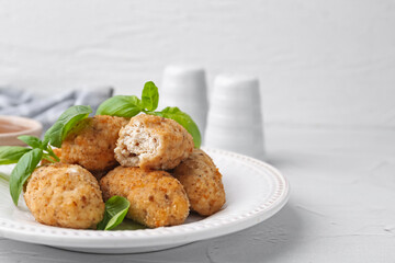 Tasty fried croquettes and basil on white textured table, closeup. Space for text