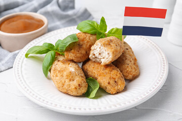 Tasty fried croquettes, basil, flag of Netherlands and sauce on white textured table, closeup