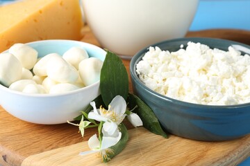 Different fresh dairy products and flowers on table, closeup