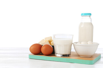 Different dairy products and eggs on wooden table against white background
