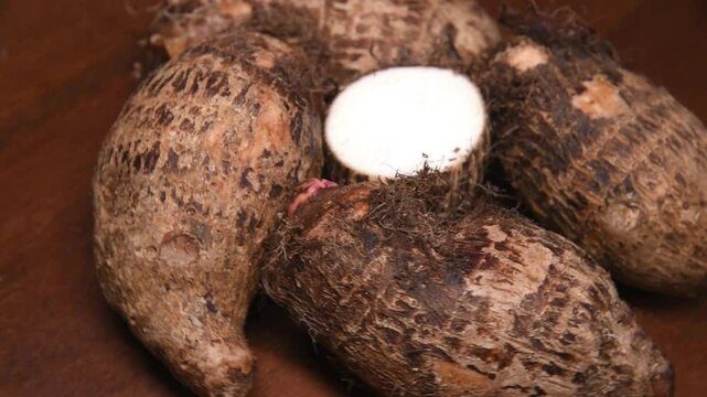 Yam on a rustic wooden background. In portuguese: Inhame. Video with rotating movement.