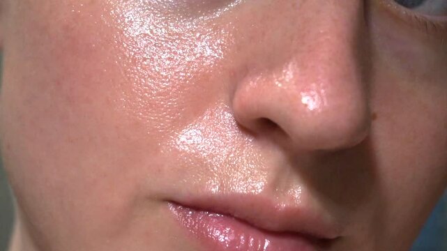 Macro shot of woman&rsquo;s glowing facial skin under daylight, showcasing pores, smooth surface and natural oil shine, ideal for skincare, beauty, cosmetic themes.