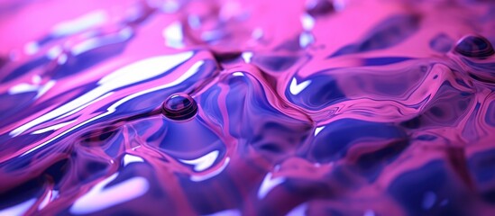 Purple water drops on a metallic blue surface create a vibrant liquid art pattern with a ripple effect