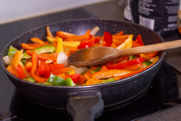 Healthy Home-Cooked Peppers with Olive Oil and Onion and Wooden Spoon.