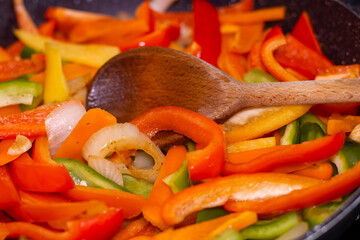 Healthy Home-Cooked Peppers with Olive Oil and Onion and Wooden Spoon.