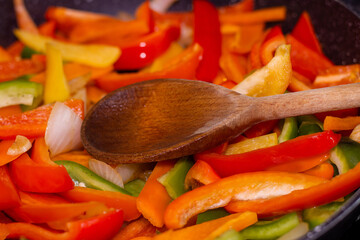 Healthy Home-Cooked Peppers with Olive Oil and Onion and Wooden Spoon.
