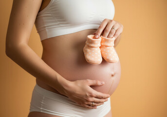Expecting mother holding tiny baby booties near her belly