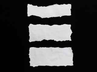 Fototapeta premium Set of ripped white paper isolated on a black background. Torn paper with clipping path. Torn paper texture with wavy edges.