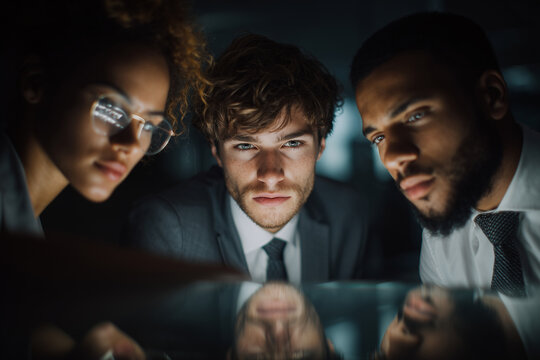 Focused diverse business team working late in office, analyzing data and collaborating on project