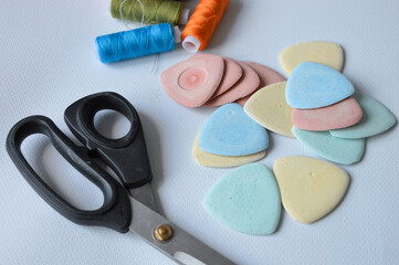 colorful sewing supplies including spools of thread tailor’s chalk scissors arranged on a white...
