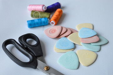 colorful sewing supplies including spools of thread tailor’s chalk scissors arranged on a white...