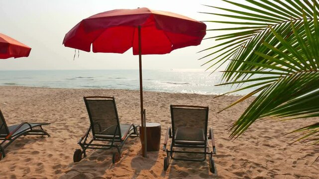 Beach chairs under a red umbrella on a sunny tropical beach