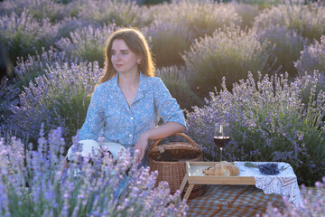Young woman kneeling in lavender field touching flowers