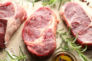 Pieces of raw beef meat and spices on parchment paper, above view