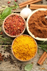 Different aromatic spices on wooden table, flat lay