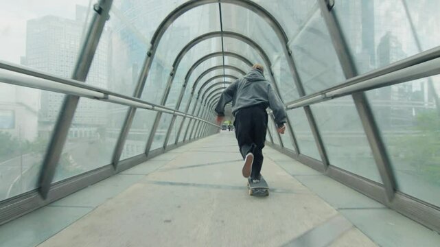 Skateboarder riding through glass tunnel in , paris