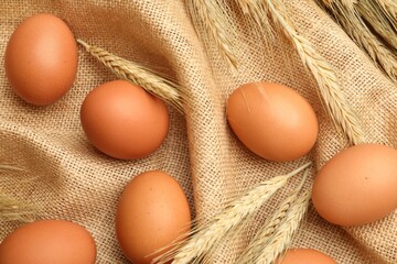 Fresh eggs and spikes on burlap cloth, top view