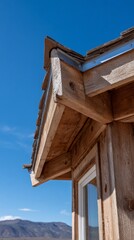 Rustic wooden roof corner with shake edge and eaves under clear sky.